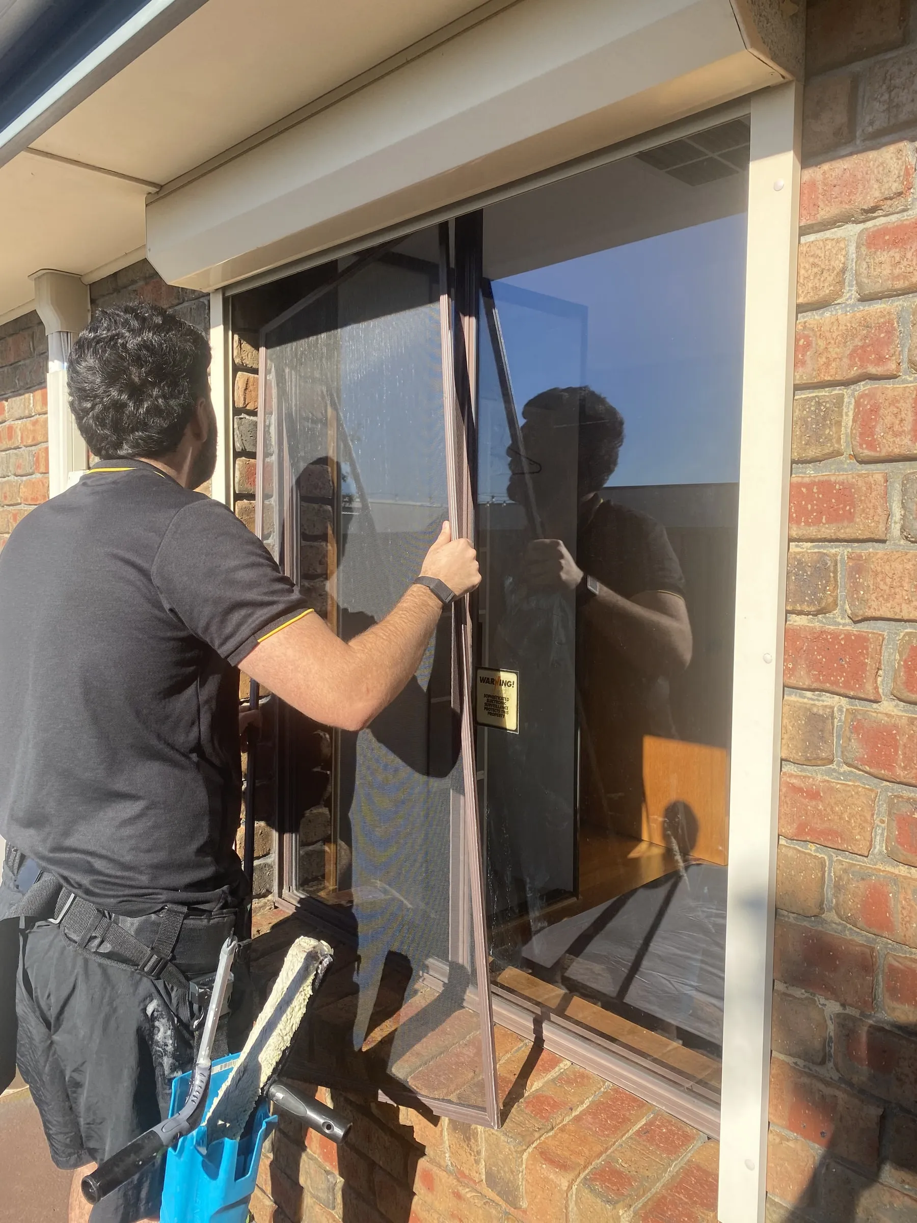 Ben cleaning a window with a squeegee, reflected in the glass