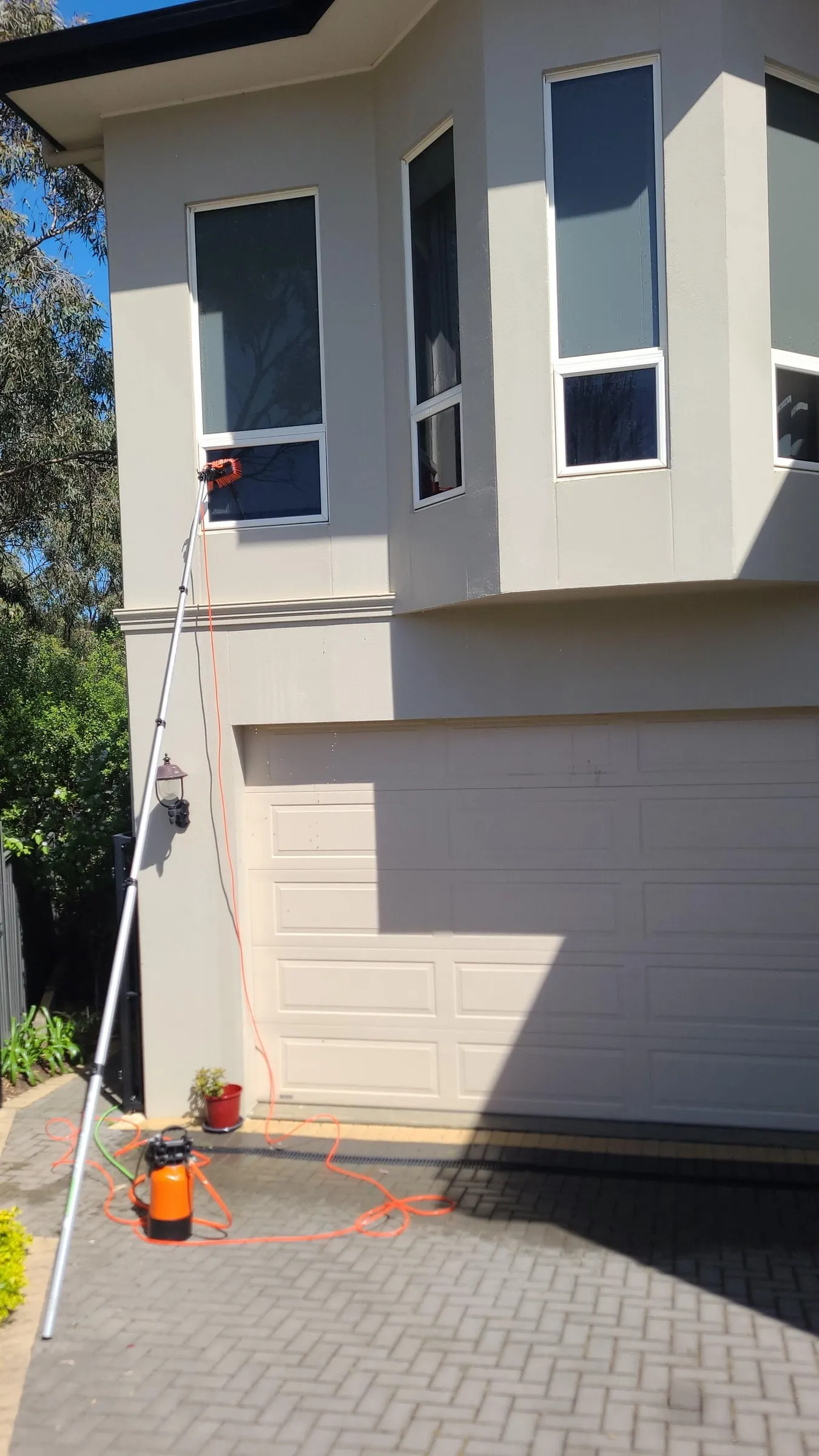 Upper-storey windows of a two-storey home cleaned by pole